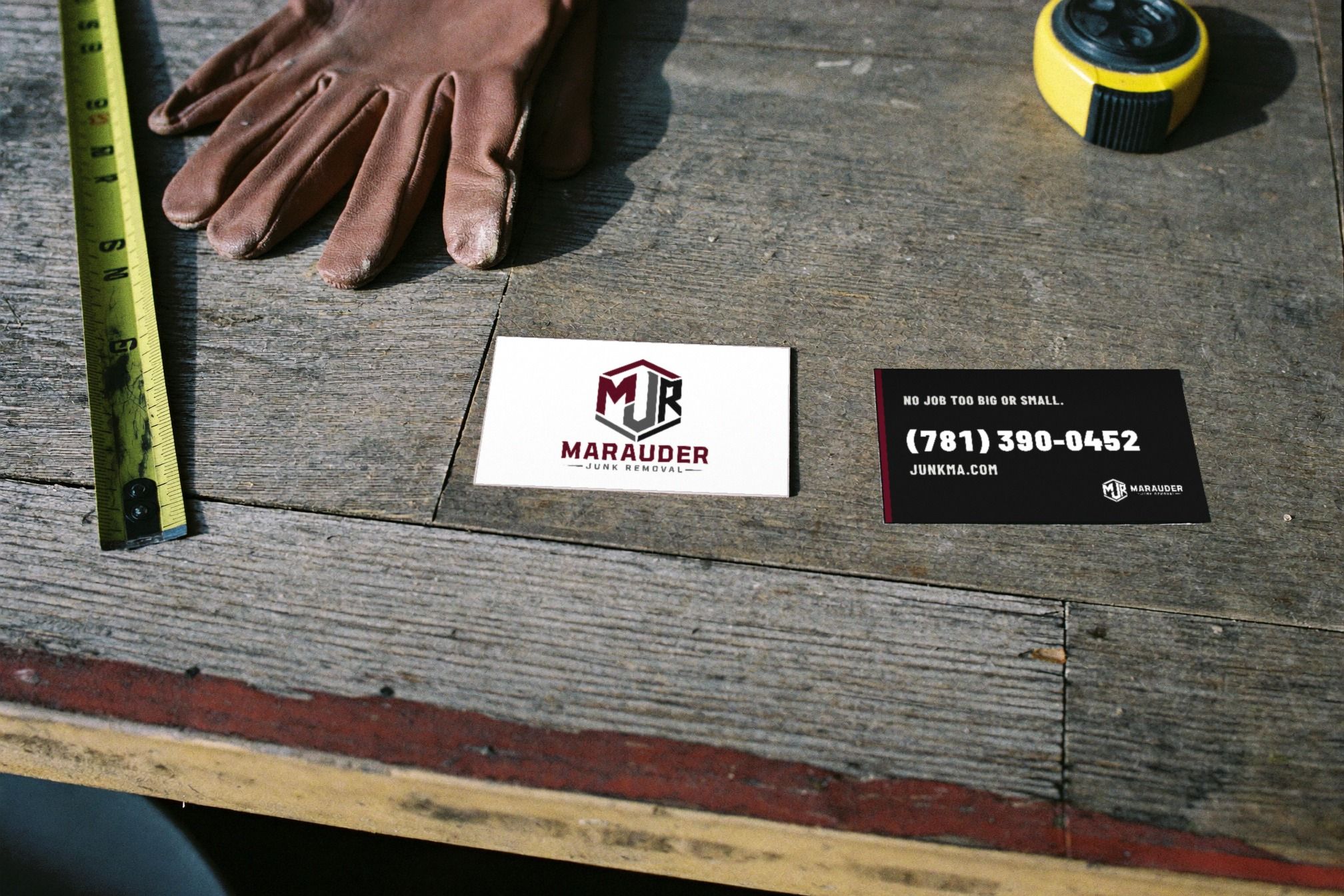 Marauder business cards, leather work gloves and a tape measure on a weathered wooden workbench